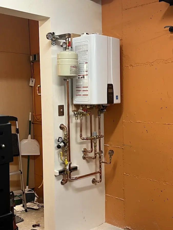Plumbing technician inspecting water heater connections in Cedarhurst